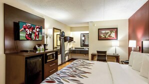 Une chambre d’hôtel comprenant un lit, un bureau, une télévision, un miroir et une salle de bain.