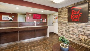 Un espace d’accueil avec une enseigne Red Roof Inn, un écran numérique indiquant la présence d’une connexion Wi-Fi gratuite, et un comptoir de réception équipé d’un ordinateur et d’un téléphone.