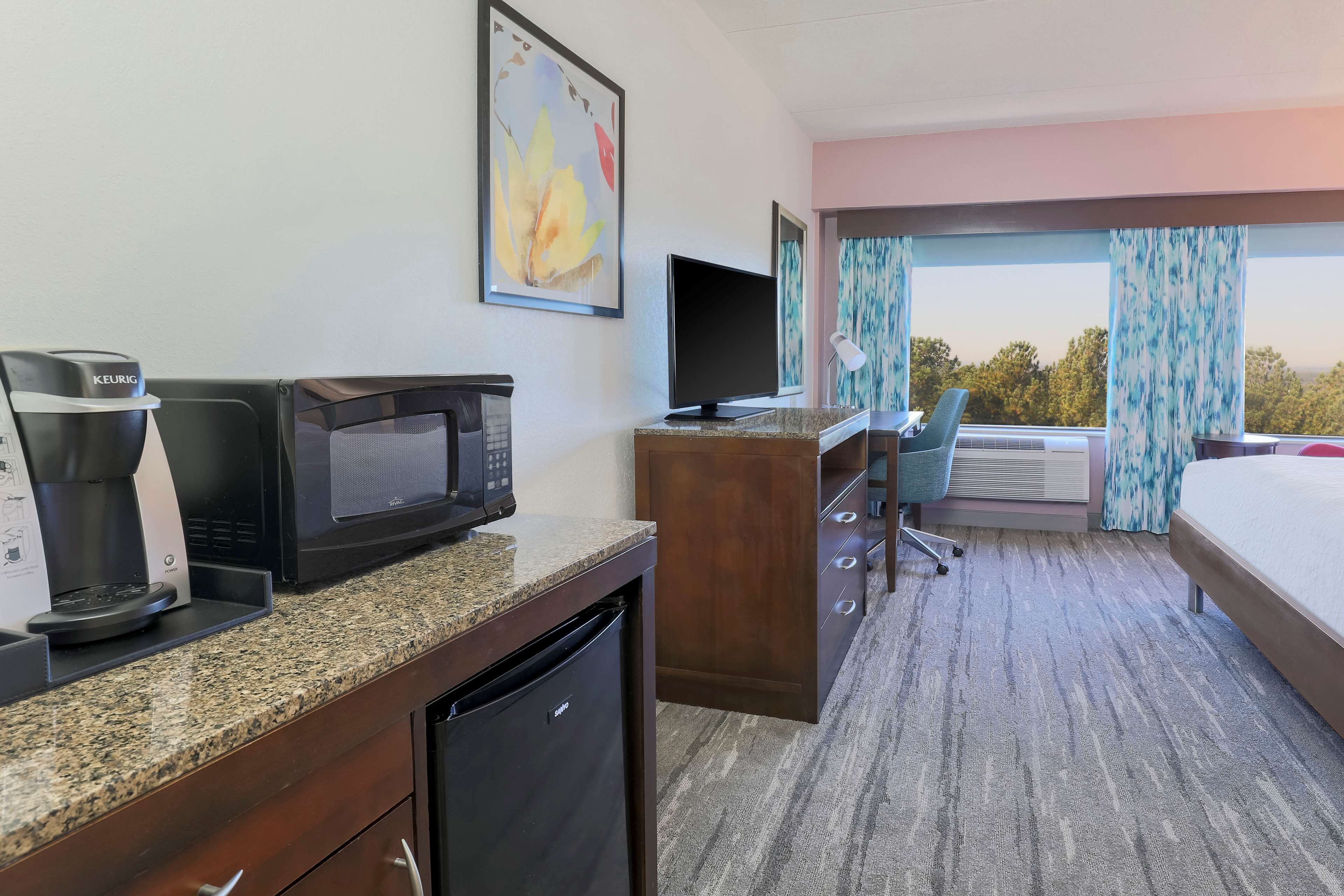 Una habitación de hotel con kitchenette, televisión, escritorio y cama.