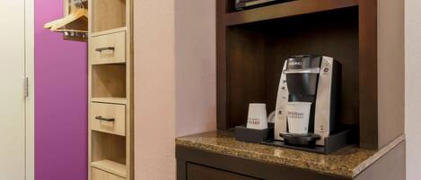 A kitchenette with a microwave, coffee maker, and a cabinet with drawers.
