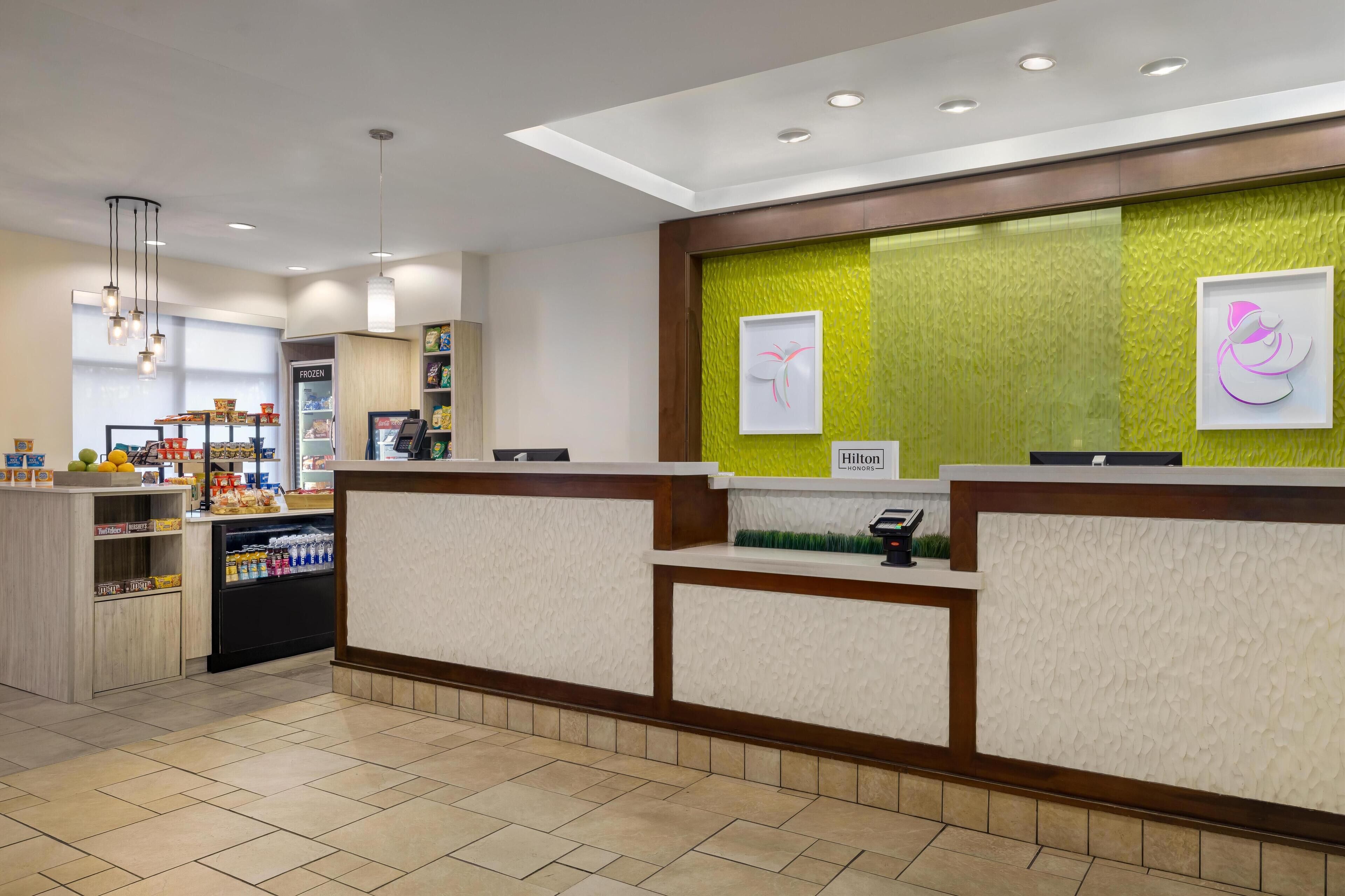 A hotel reception area with a counter, a refrigerator, and a display of snacks.