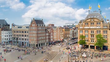 A historic square with tram lines and a variety of buildings, including a prominent building with "DE BIEJENKORE" signage.