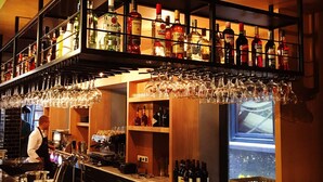 A bar area with shelves of liquor bottles, glasses, and a bartender preparing drinks. - Swissôtel Amsterdam (Amsterdam)