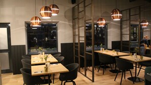 A modern restaurant interior with wooden tables, black chairs, and copper pendant lighting. - Swissôtel Amsterdam (Amsterdam)