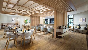 A modern dining area with wooden flooring, round tables, and light grey chairs. - voco Vienna Prater by IHG (Vienna)