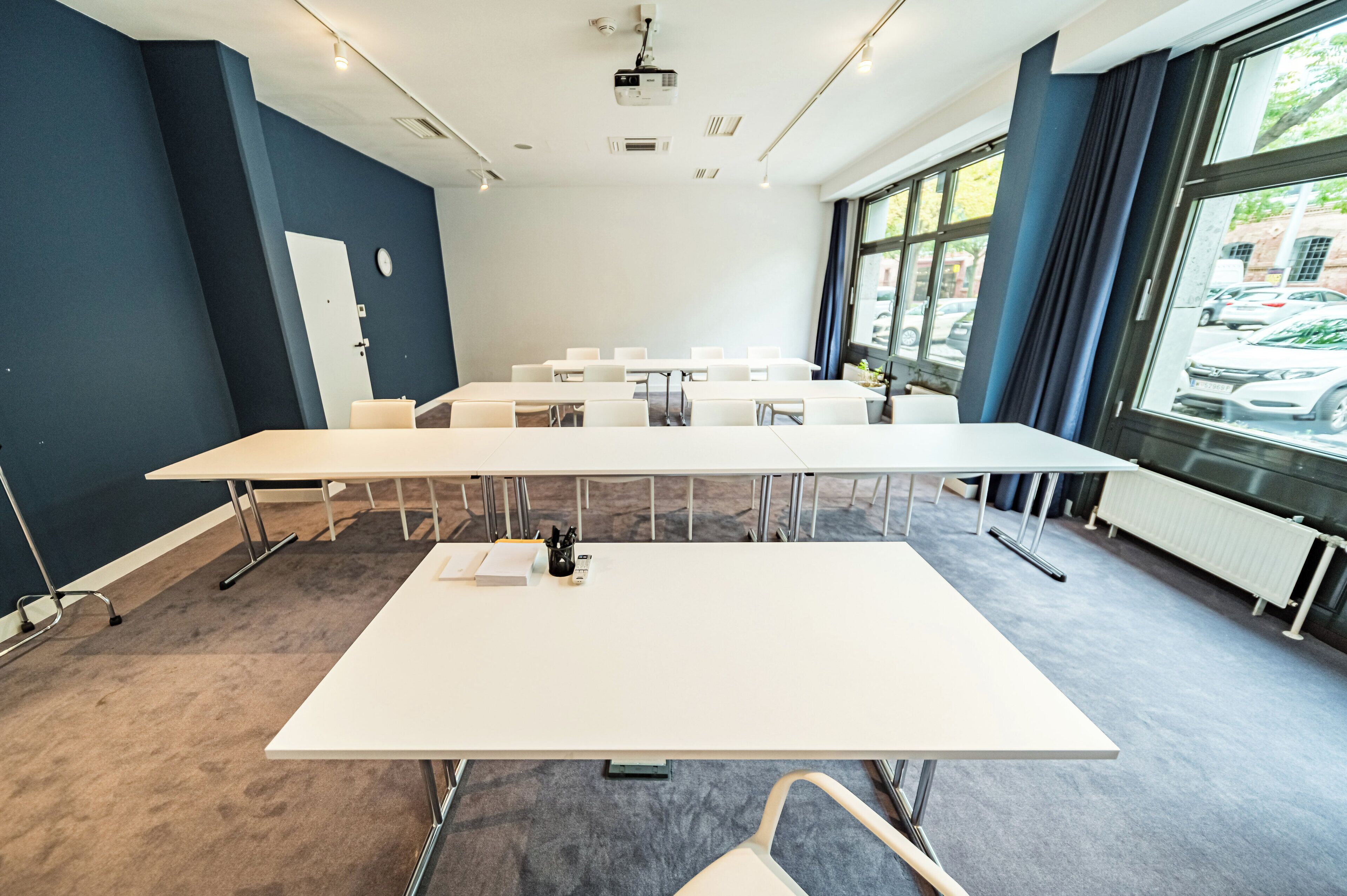 Uma sala de conferência com uma mesa comprida, cadeiras, um projetor e uma lousa.