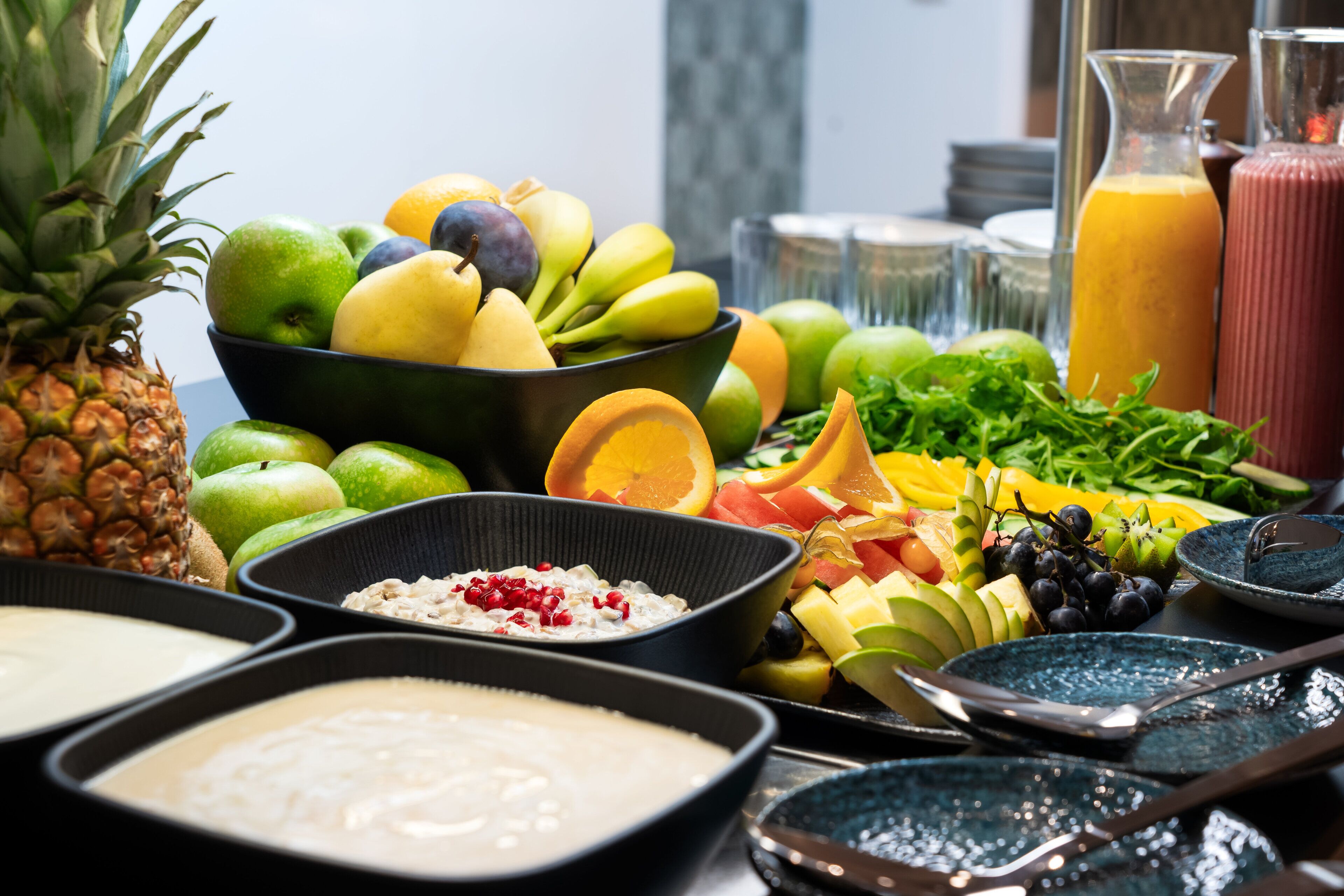 A buffet with various fruits, vegetables, and beverages.