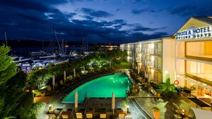 Un hotel con piscina, zona de estar al aire libre y vista al puerto deportivo.