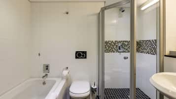 A modern bathroom with a bathtub, toilet, and glass-enclosed shower.