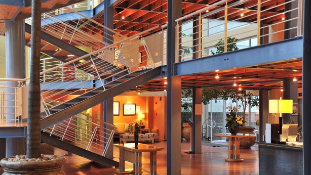 Un vestíbulo amplio con una escalera central, zonas de estar y un mostrador de recepción.