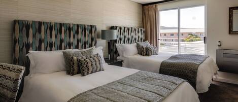 A hotel room with two beds, a large window, and a view of the outside.