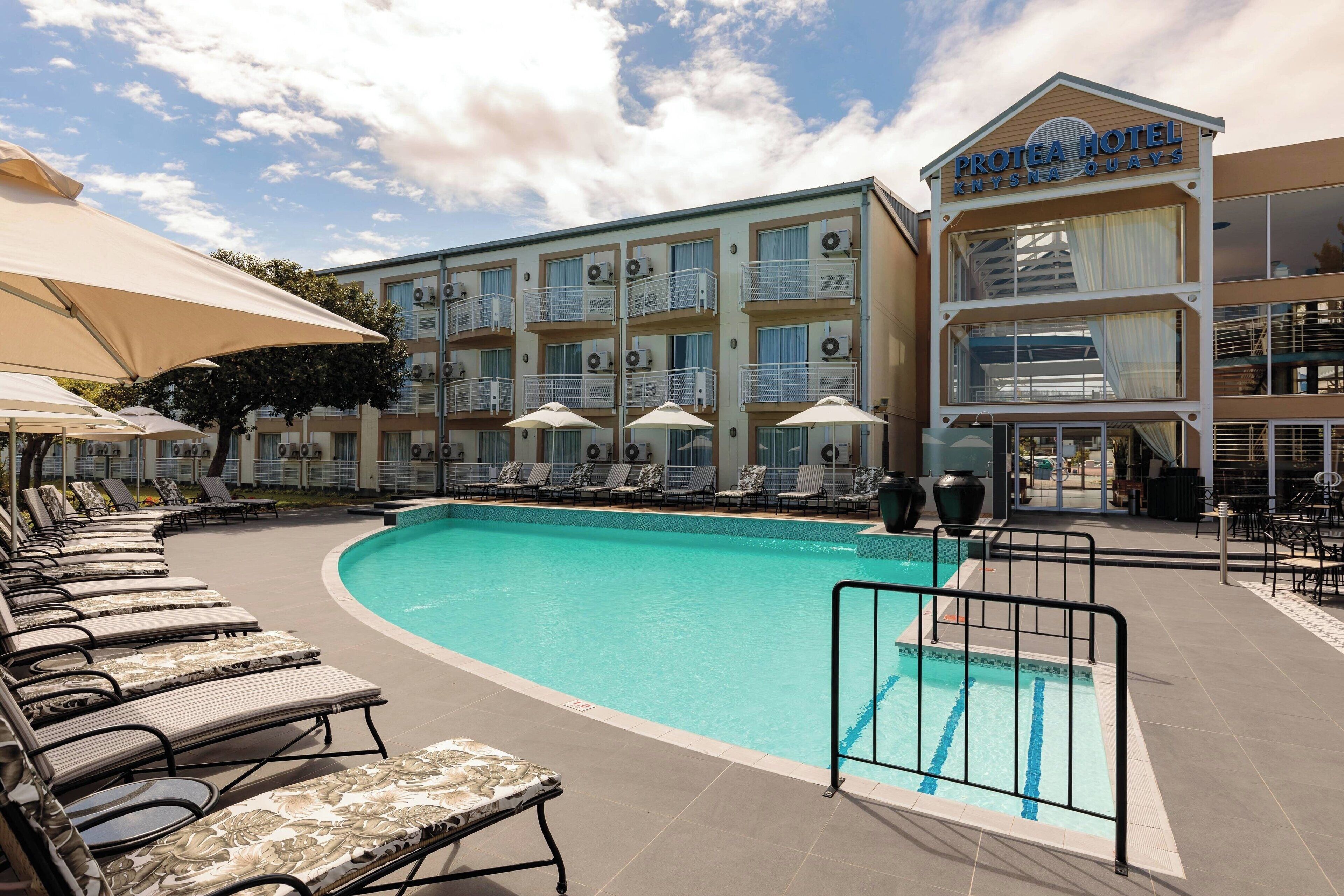 Un hotel con piscina, tumbonas y sombrillas.
