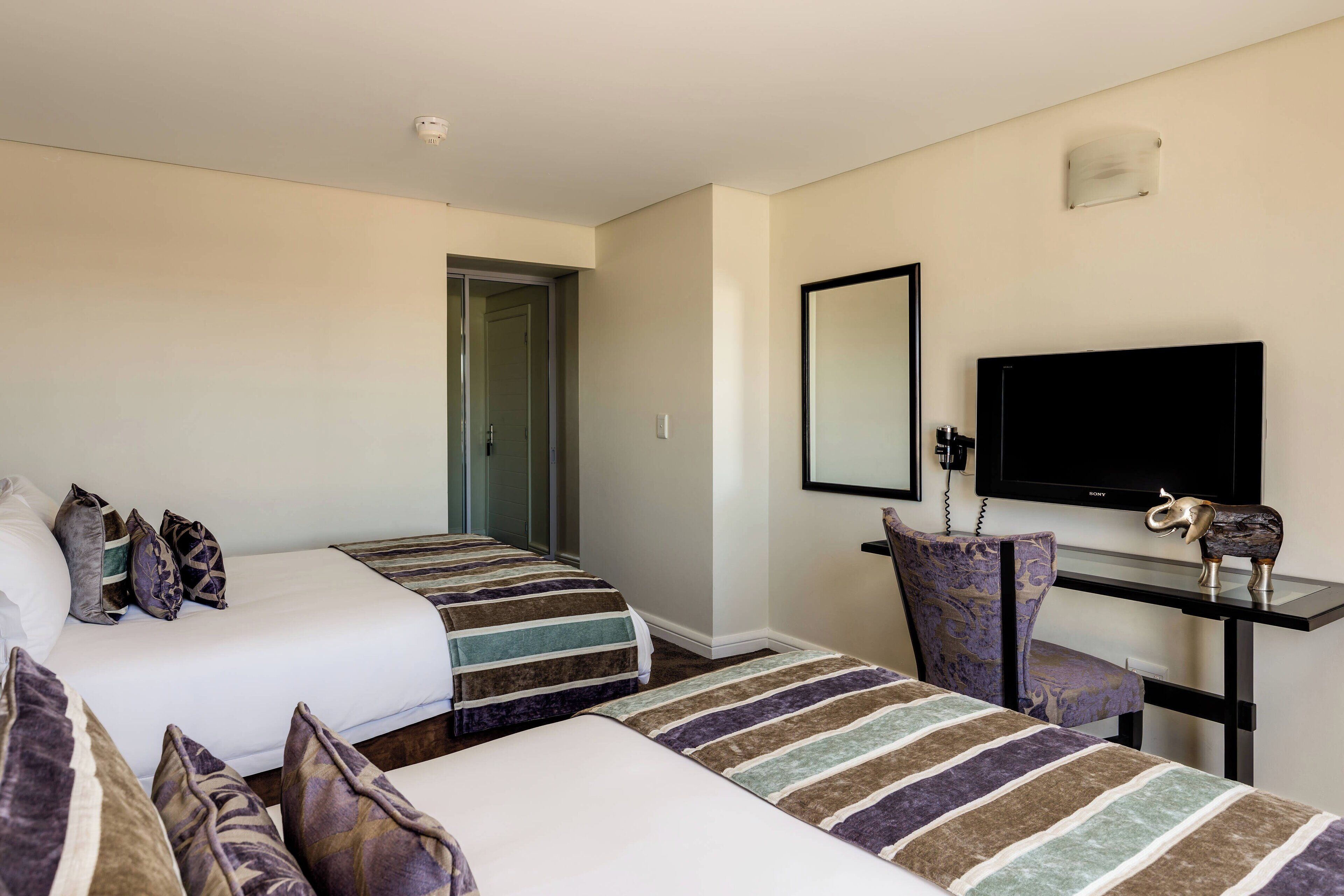Habitación de hotel con dos camas, televisión, escritorio y una silla.