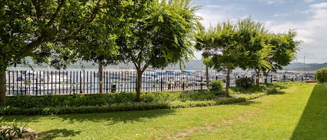 Un parque con valla, árboles y vista de coches estacionados.
