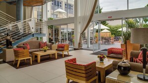 Un espacio interior amplio con una escalera, arreglos de asientos y vista del patio exterior.