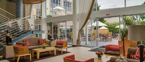 A spacious indoor area with a staircase, seating arrangements, and a view of the outdoor patio area.