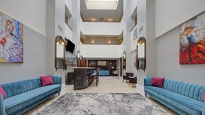 A spacious atrium with high ceilings, a central seating area, and artwork on the walls. - The Roslyn, Tapestry Collection by Hilton (Roslyn)