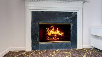 A fireplace with a fire, a white mantel, and a patterned carpet.