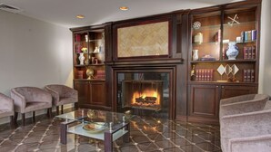 A living room with a fireplace, bookshelves, and comfortable seating. - The Roslyn, Tapestry Collection by Hilton (Roslyn)