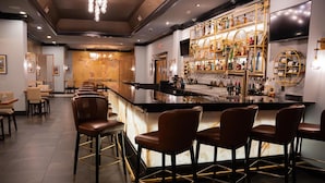 A bar area with a marble countertop, bar stools, and a well-stocked liquor shelf. - The Roslyn, Tapestry Collection by Hilton (Roslyn)