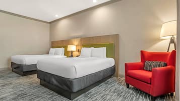 A hotel room with two beds, a red armchair, a lamp, and a patterned carpet.