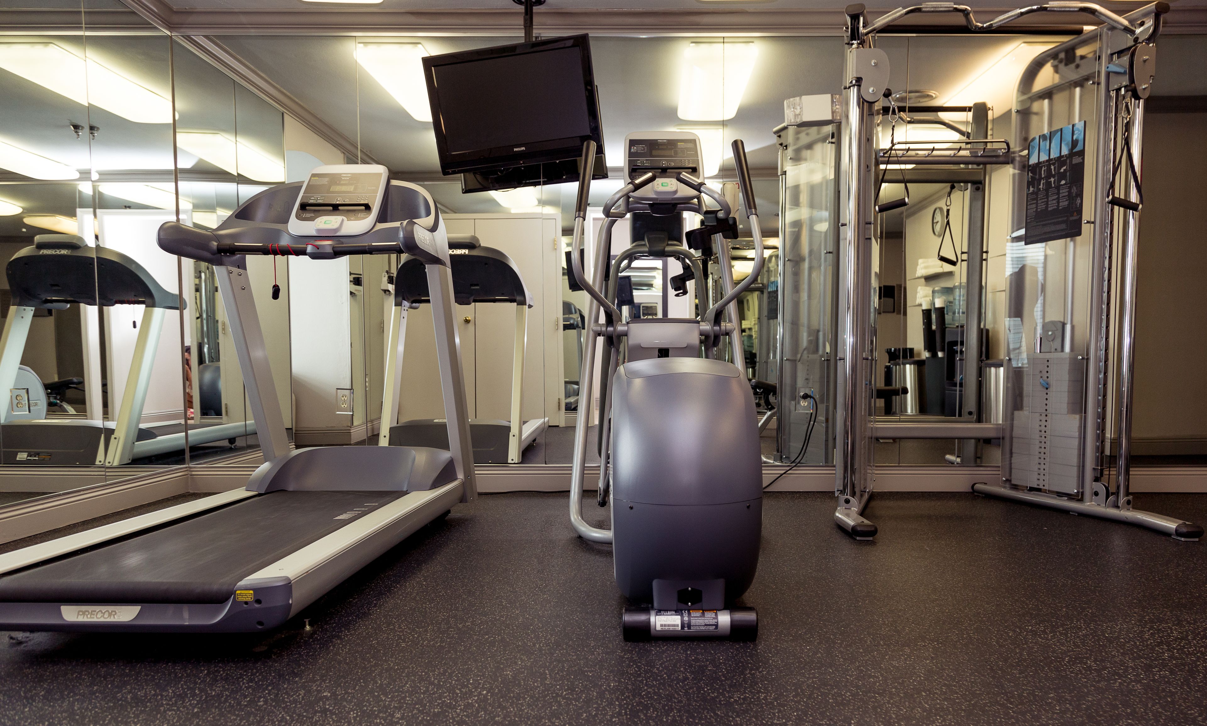 Un gimnasio con cintas de correr, elípticas y equipo de levantamiento de pesas.
