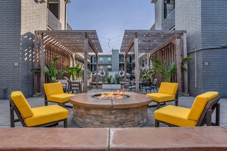 Un cortile con un braciere, sedie gialle e un pergolato.. Country Inn & Suites by Radisson, Metairie (New Orleans), LA