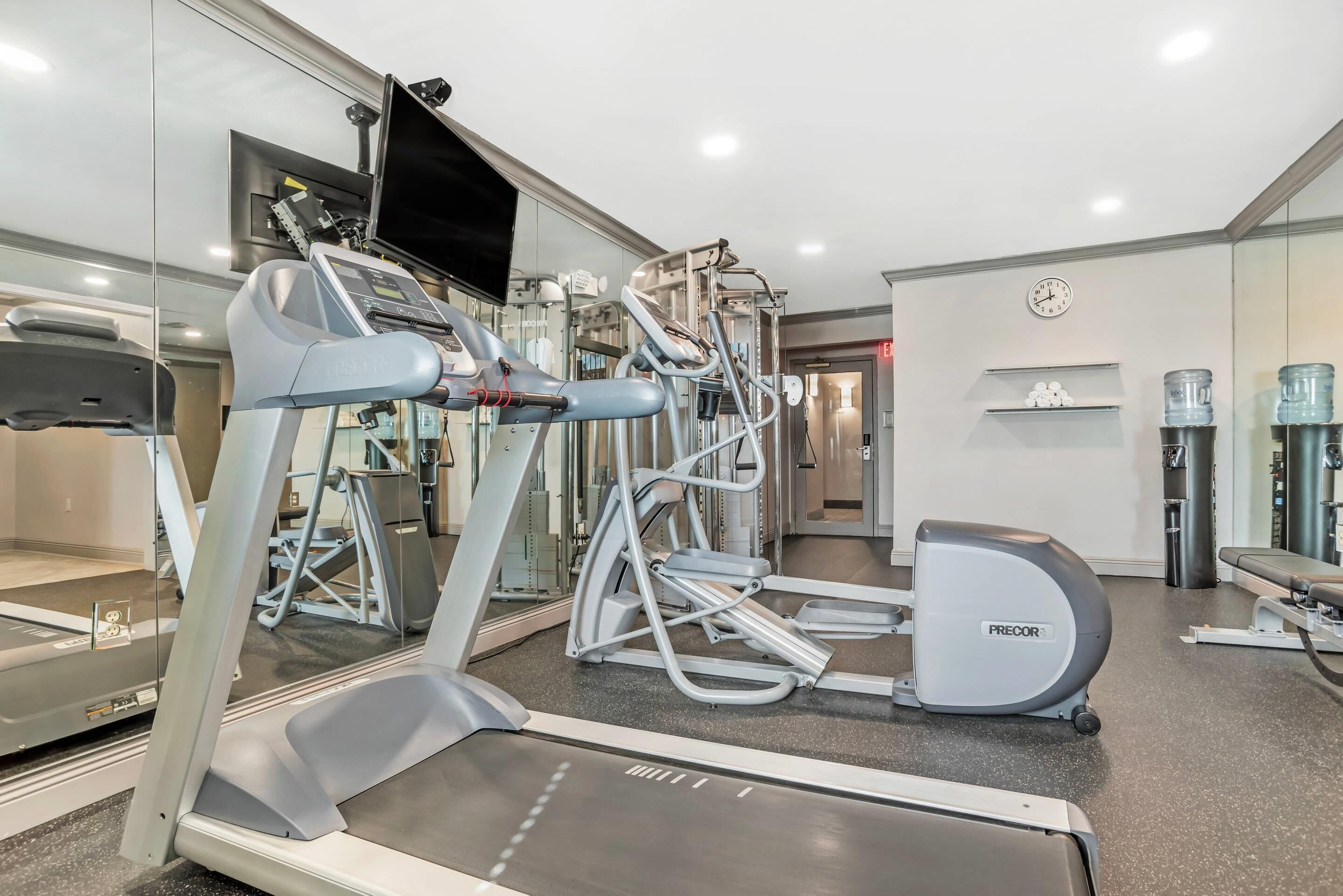 A modern gym with treadmills, elliptical machines, and weight equipment.