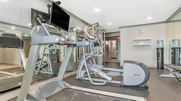 A modern gym with treadmills, elliptical machines, and weight equipment.