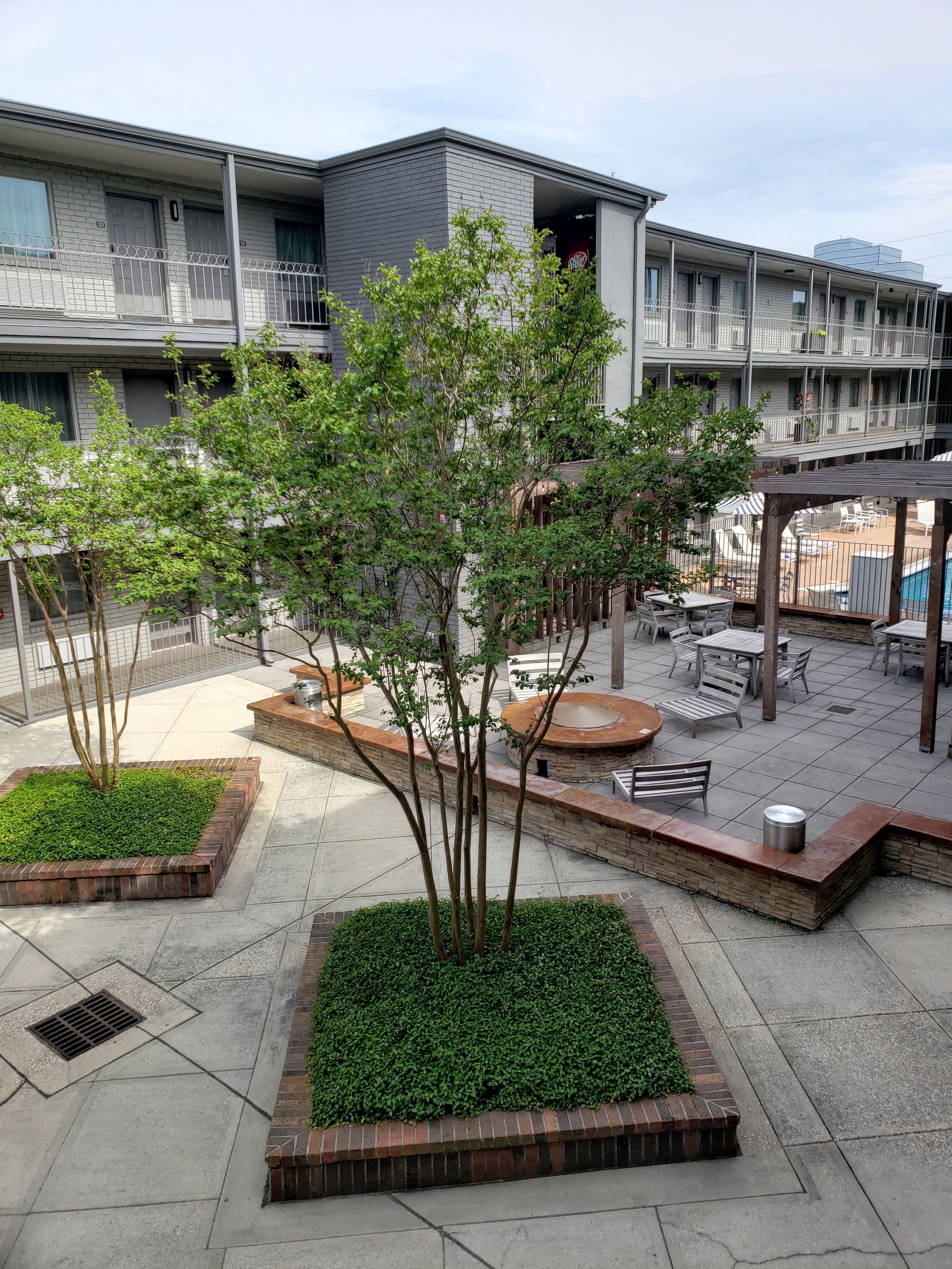 A rooftop patio with outdoor seating, a pool, and a modern building in the background.