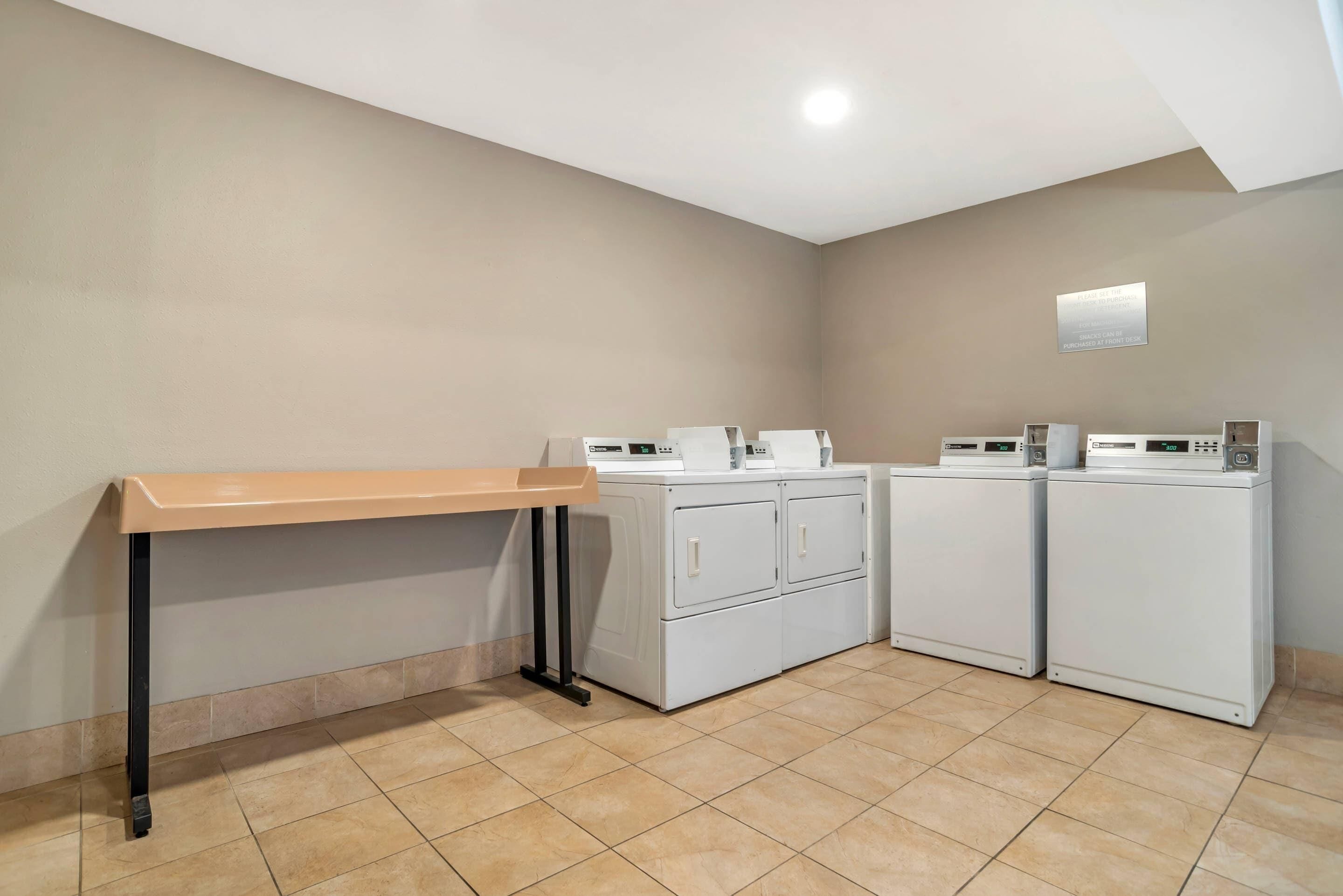 A laundry area with a bench, two washing machines, and a dryer.