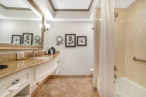 Ein Badezimmer mit einem Doppelwaschbecken, einem großen Spiegel, gerahmten Kunstwerken an der Wand, einer Toilette und einer Duschkabine.