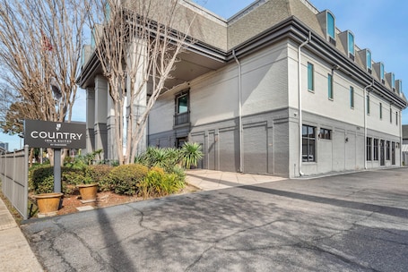 A building with a sign reading 'COUNTRY INN & SUITES' by RADINSON, featuring a modern design with a flat roof, large windows, and a paved driveway.. Country Inn & Suites by Radisson, Metairie (New Orleans), LA