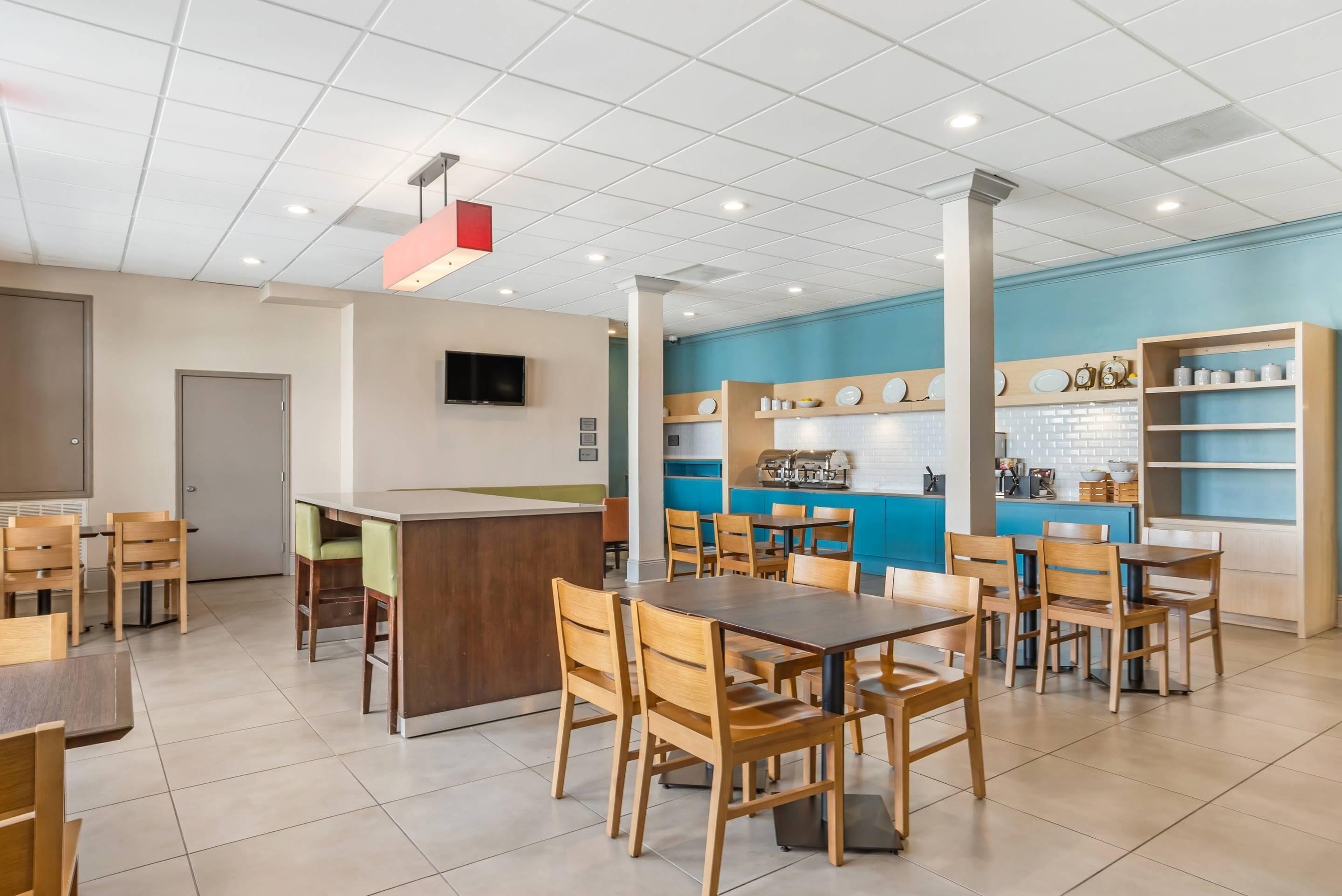 A modern dining area with a central bar, multiple tables and chairs, and a kitchen area in the background.