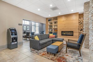 A modern living room with a sectional sofa, a coffee table, a fireplace, and a fireplace screen. - Country Inn & Suites by Radisson, Metairie (New Orleans), LA (Metairie)