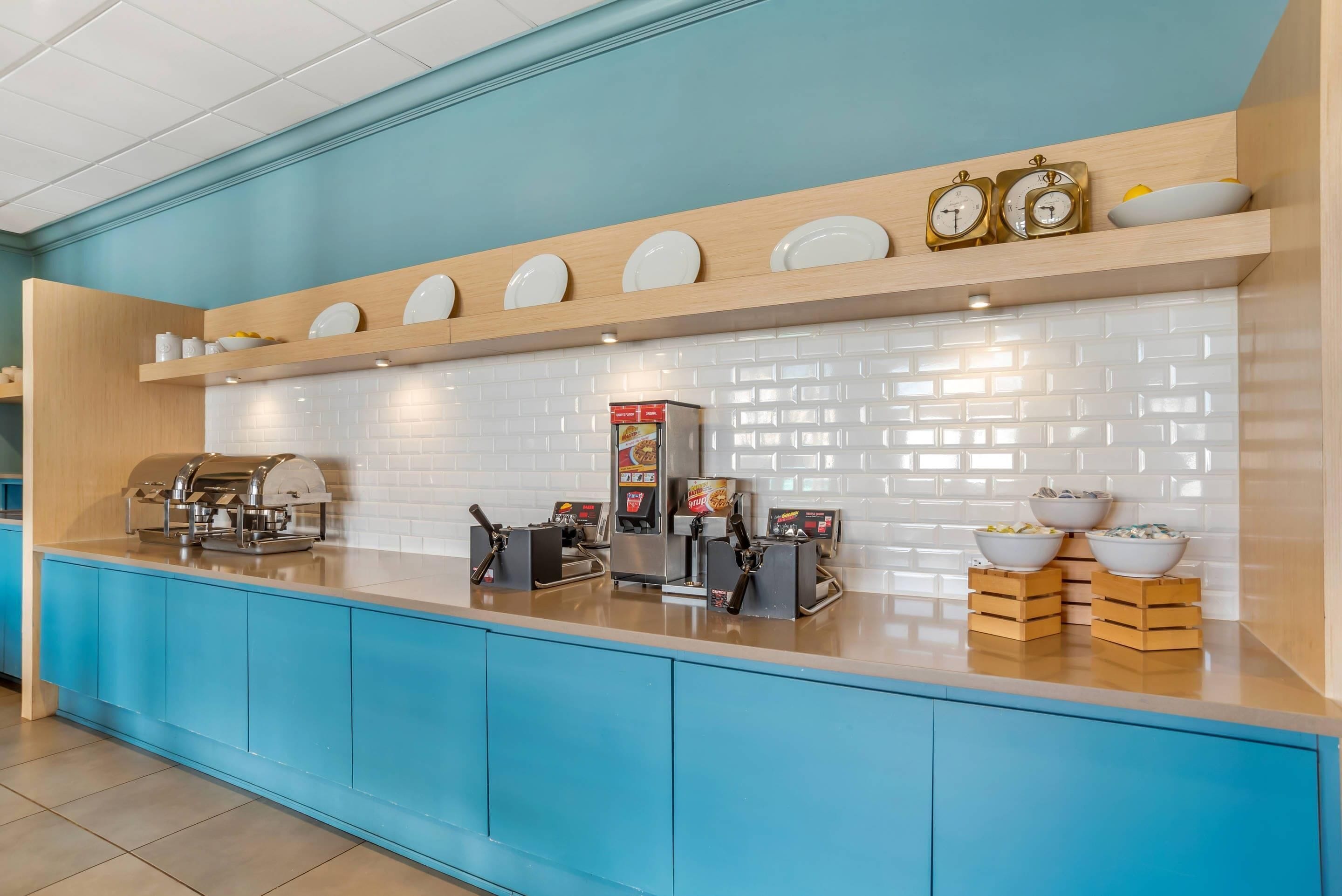 Un banco buffet con distributori di cibo, una macchina per caffè e uno scaffale con piatti e ciotole.