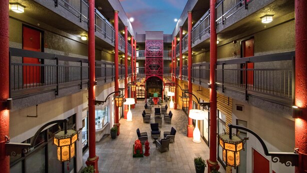 Ein mehrgeschossiges Hotel-Atrium mit einer zentralen Treppe, Sitzbereichen und roten Säulen.