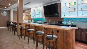 Eine Bar mit Holzhockern, einer Theke und Regalen mit Flaschen.