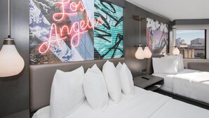 Ein modernes Hotelzimmer mit einer großen Wandmalerei, einem Bett mit weißer Bettwäsche und Blick auf die Stadt.