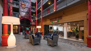 Eine Hotelhalle mit Korbmöbeln, einer Treppe und einem Restaurant namens "SUGAR HOUSE".