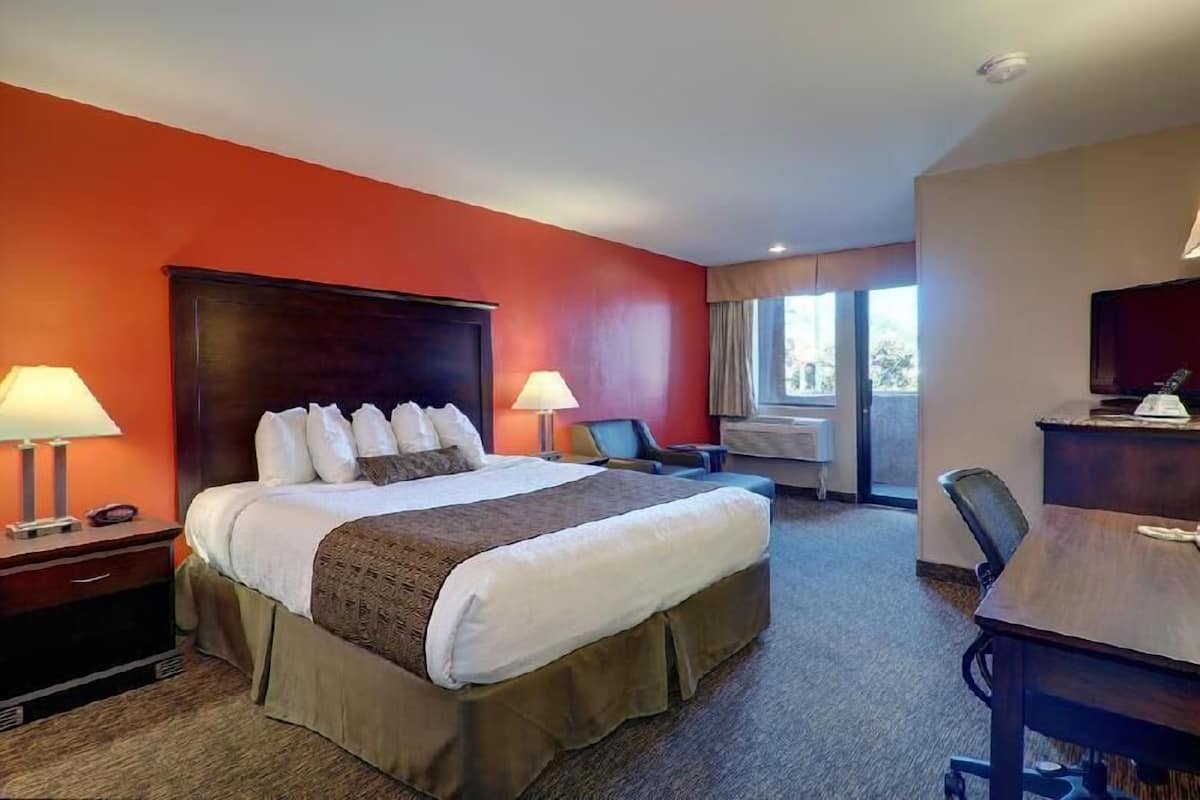 A hotel room with a large bed, two bedside tables with lamps, a desk, and a chair.