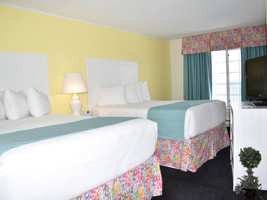 Habitación de hotel con dos camas, televisión y ventana con cortinas.