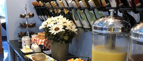 A bar area with a variety of wine bottles, a fruit platter, and a beverage dispenser.