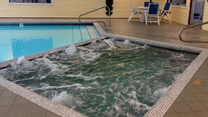 A pool area with a hot tub, lounge chairs, and a lifebuoy on the wall.