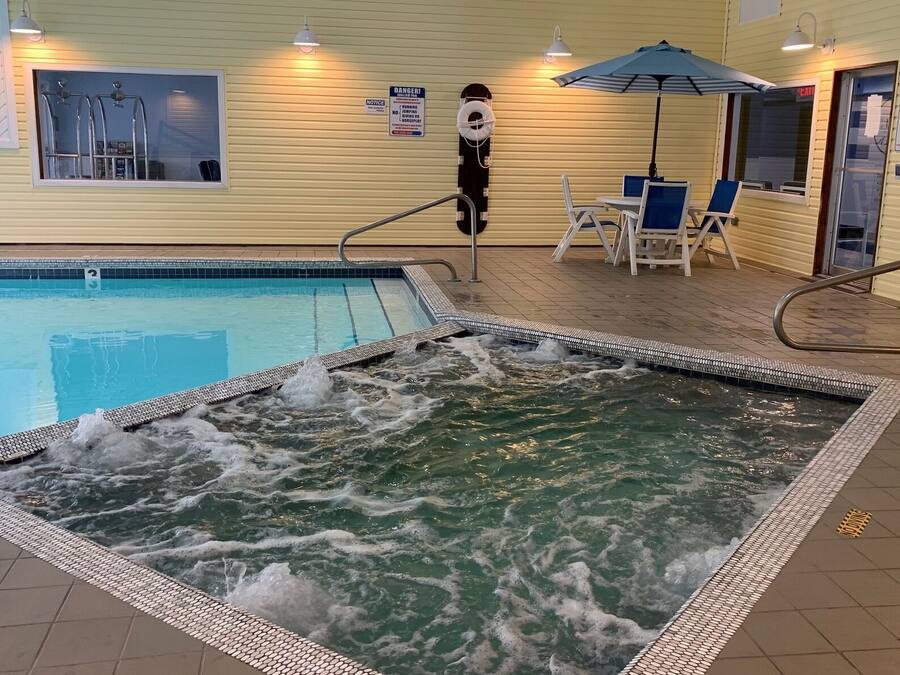 Zona de piscina con jacuzzi, sillas de descanso y un flotador en la pared.