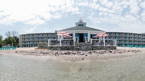 A beachfront hotel with a central pavilion, multiple balconies, and outdoor seating with umbrellas.