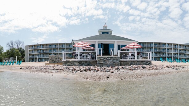 A beachfront hotel with a central pavilion, multiple balconies, and outdoor seating with umbrellas. - Breakers Resort & Beach Bar (St Ignace)