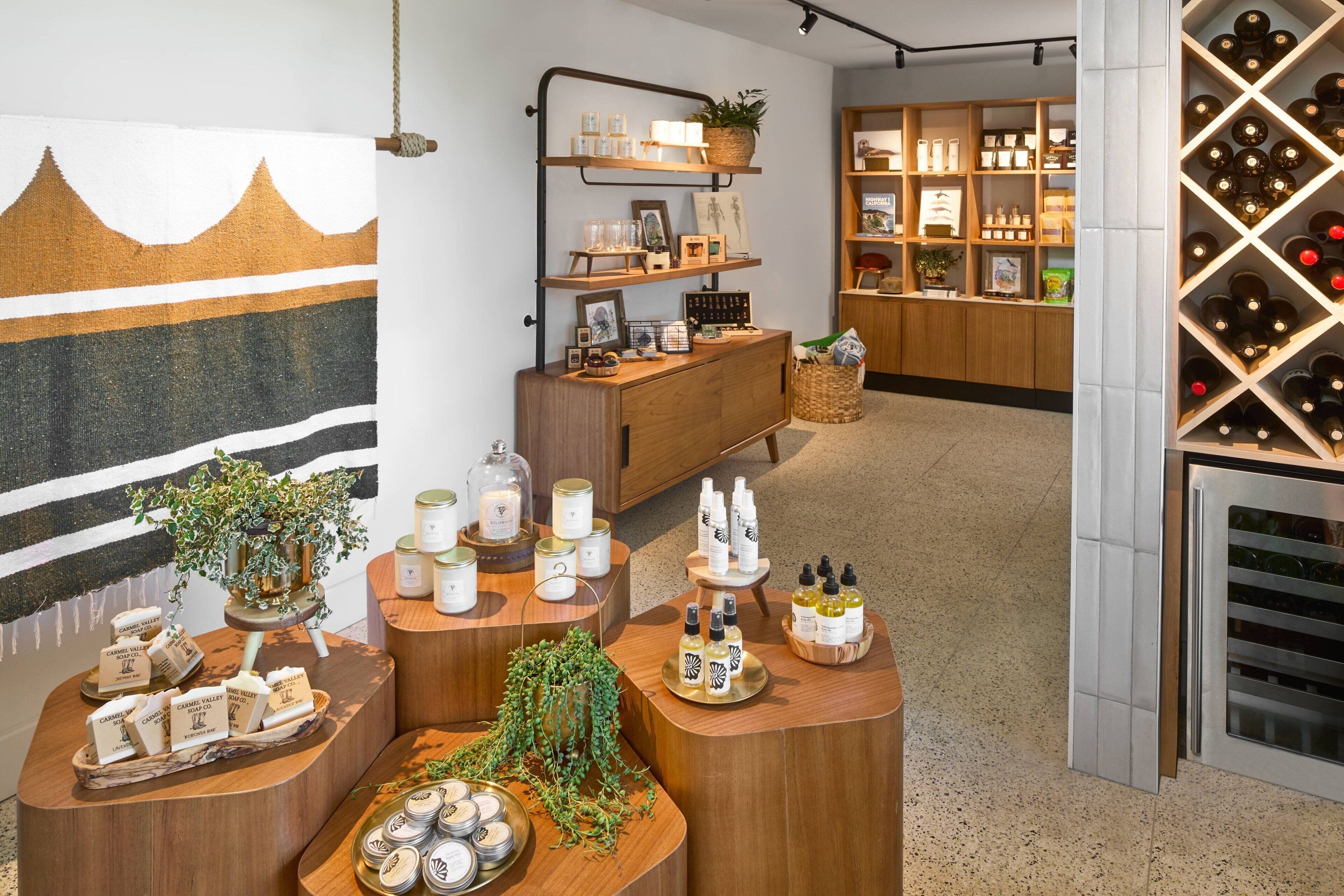 Un lobby de hotel boutique con muebles de madera, una exhibición de vinos y una pared con diseño de montaña.