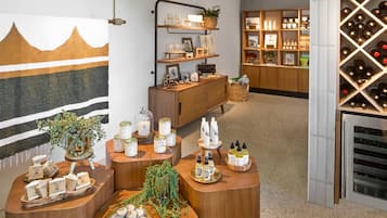 Un lobby de hotel boutique con muebles de madera, una exhibición de vinos y una pared con diseño de montaña.