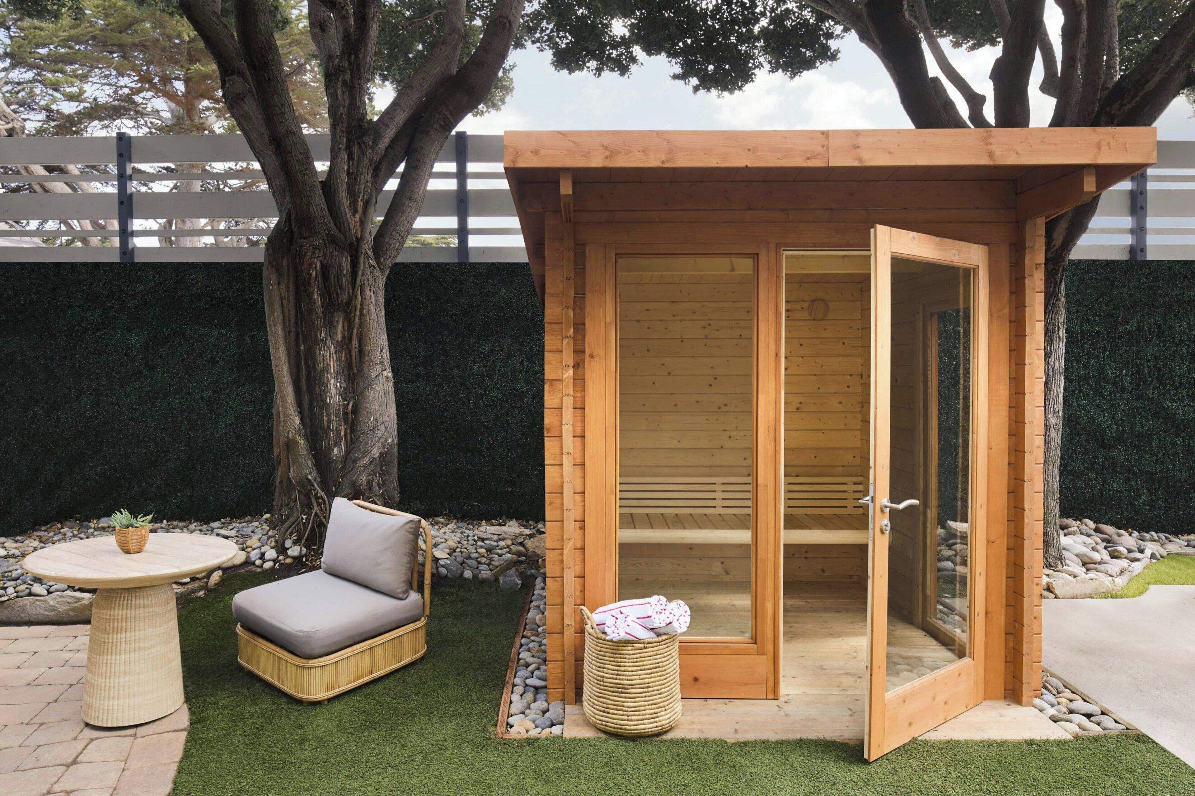 A wooden structure with a sliding door, a wicker sofa, and a small table with a plant.